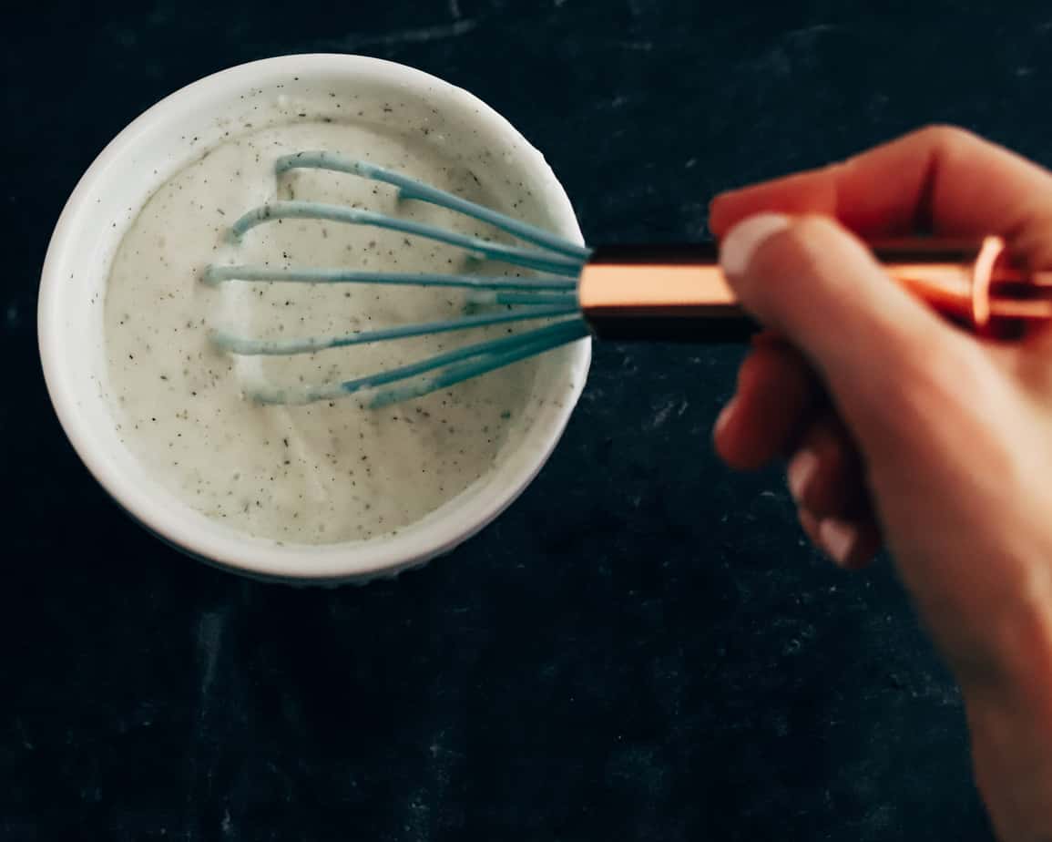 Teal silicone whisk with copper handle stirs together buttermilk and Ranch dressing seasoning