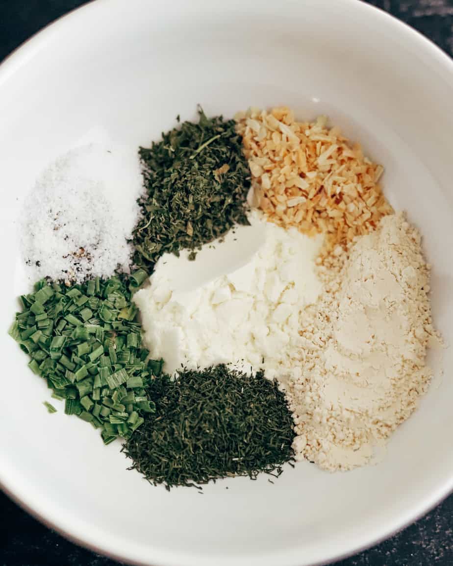 Shallow porcelain bowl contains herbs and spices to make Ranch seasoning