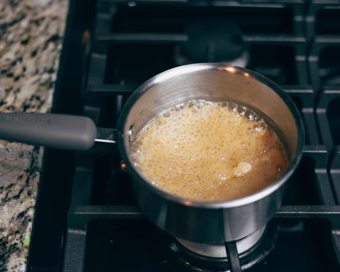Pot of coconut milk and sugar begins to bubble as it heats up