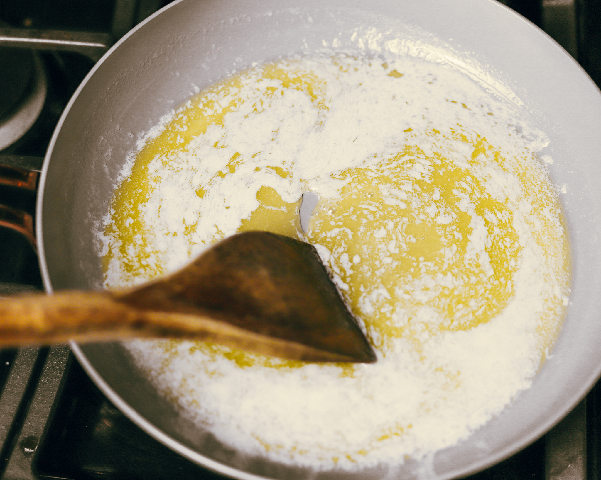 wood spoon stirs foaming butter as it heats up in a pan
