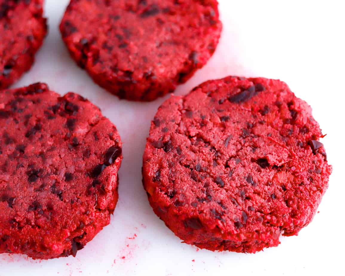 Beet and sweet potatoes are formed into veggie burger patties on a cutting board
