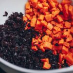Cubed sweet potatoes and shredded beets are combined in a white mixing bowl