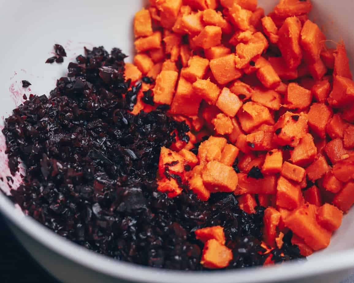 Cubed sweet potatoes and shredded beets are combined in a white mixing bowl