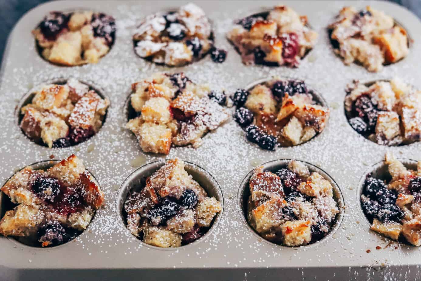 Muffin tray of french toast and blueberry dusted with powdered sugar
