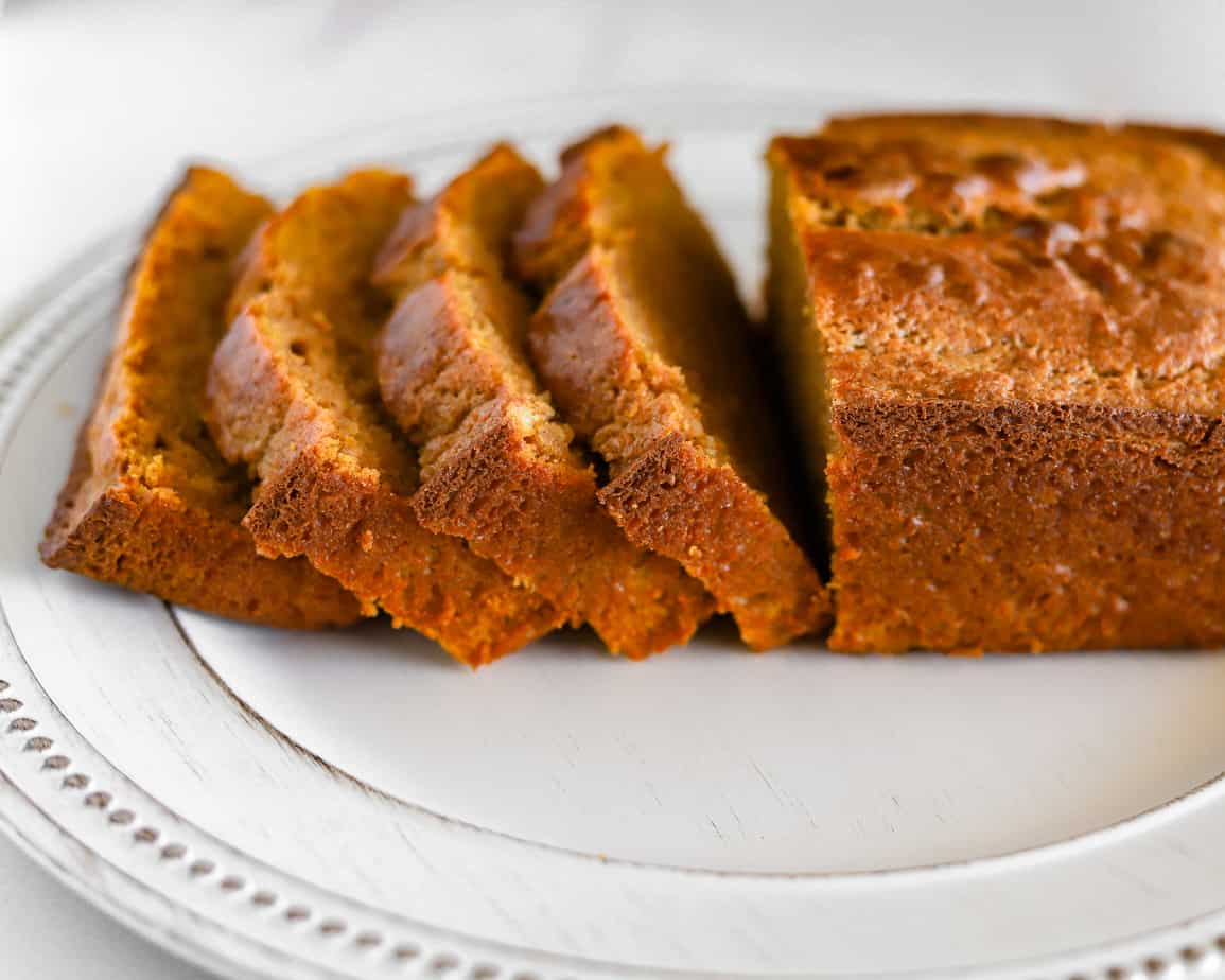 Pumpkin loaf sliced and spread across a white rustic plate