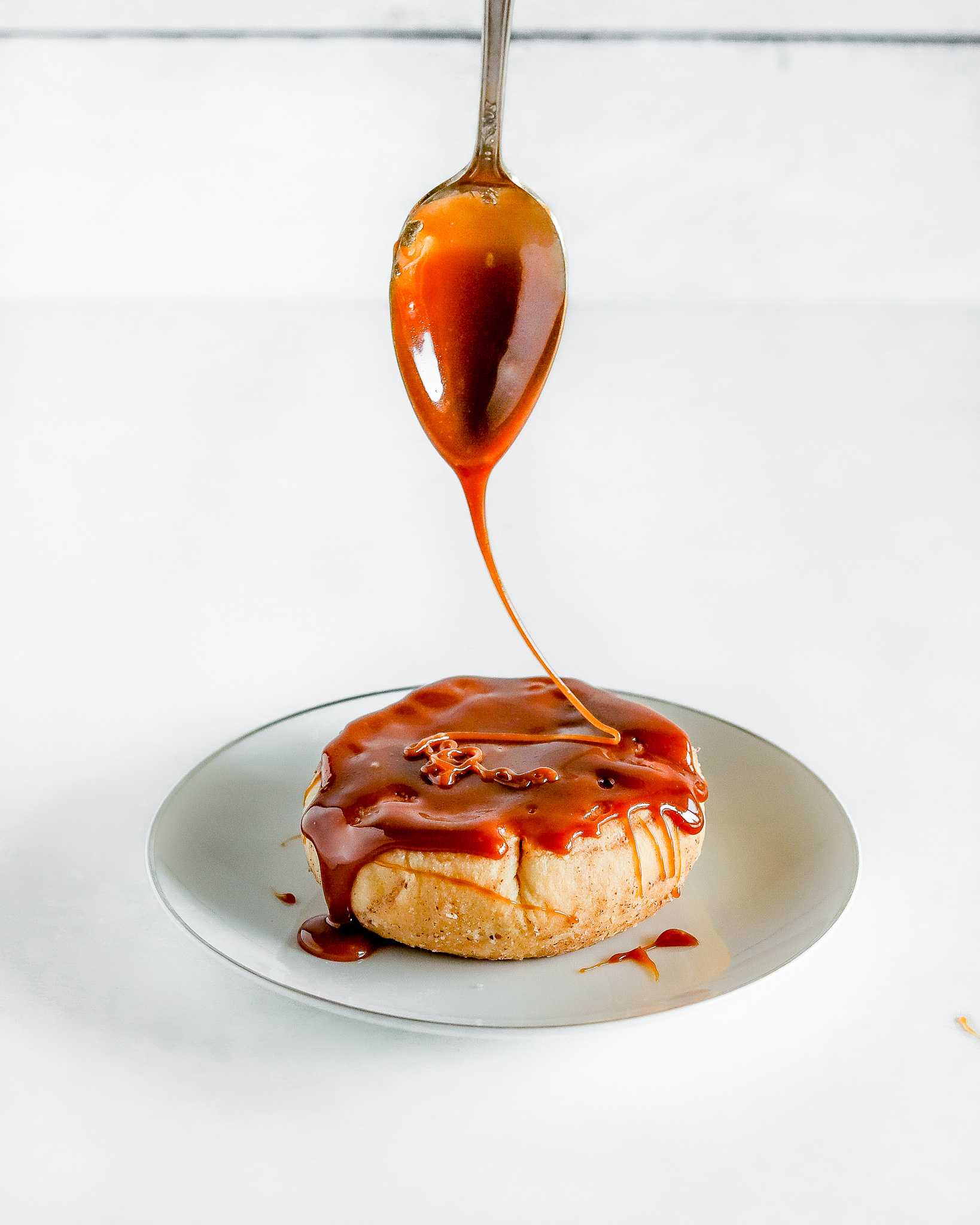 caramel on a spoon is drizzle over a freshly baked caramel apple biscuit