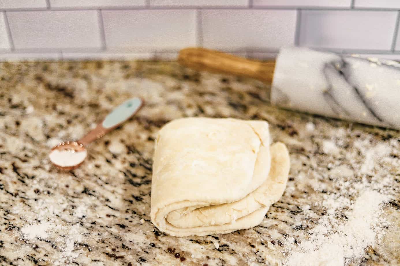 pie crust dough folded into quarters, making a triangle shape, on a floured counter top