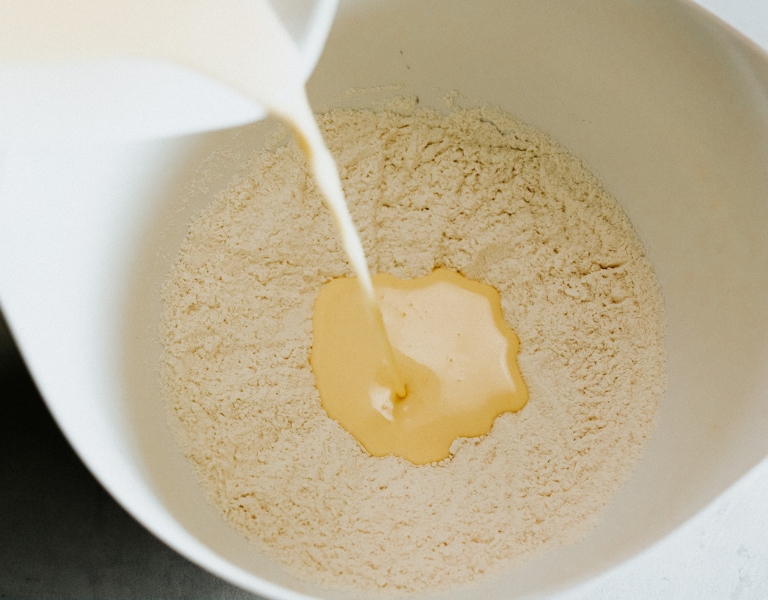 ricotta pancake batter being poured into a mixing bowl