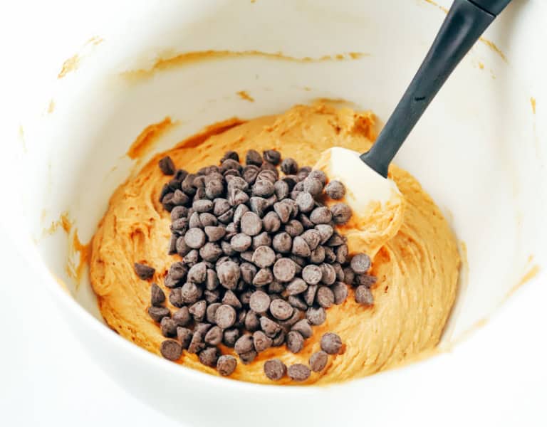 mixing bowl with pumpkin cookie dough and covered in chocolate chips before mixing together