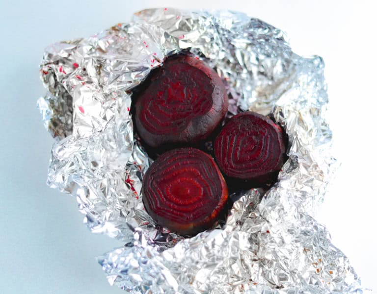 freshly roasted beets are wrapped in foil to show the steps of making a beet burger recipe