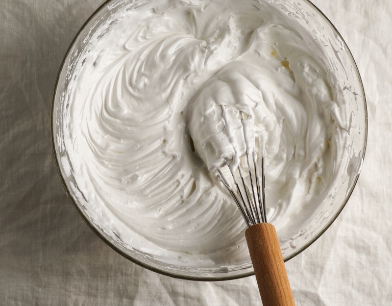 glass bowl and whisk with whipped cream